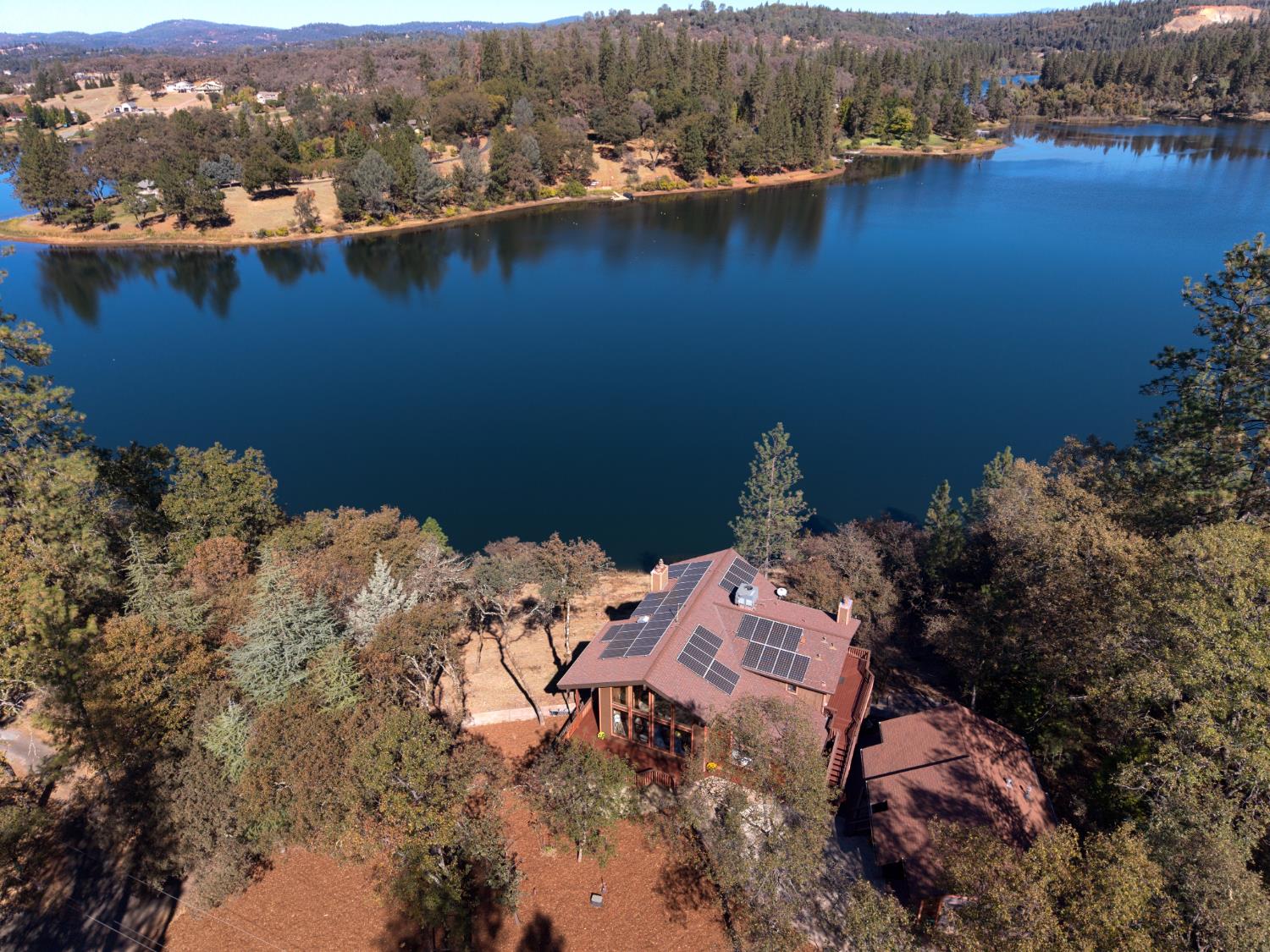 NOTHING ELSE LIKE IT ON LAKE COMBIE! Photos simply cannot capture the incredible lake views and setting of this one-of-a-kind property! First time on the market! Situated on approximately 2 private, usable acres overlooking beautiful Lake Combie, this home offers breathtaking water views from multiple levels and endless possibilities! Inside, soaring wood ceilings, exposed beams, and dramatic floor-to-ceiling windows bring the outdoors in, while expansive decking provides the perfect place to relax, entertain, and soak in those spectacular views. The home's unique architecture and warm wood accents create that true lakehouse feeling. What makes this property even more special is its versatility! In addition to the main residence, a downstairs apartment offers its own private entrance and parking, while a separate studio apartment behind the garage provides even more flexibility. Ideal for multigenerational living, extended guests, or potential rental opportunities, including short-term rentals. The usable acreage offers RV hookups, room for horses, gardens, outdoor activities, and potentially an additional dwelling. For those dreaming of enjoying the lake up close, a private dock IS possible per NID. Incredible views, privacy, usable acreage, and multiple living spaces, all in one extraordinary Lake Combie property. This is truly one you have to see in person!
